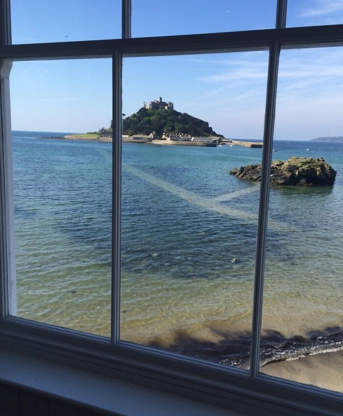 View of a famous landmark island castle from an unexpected angle through a window over clear coastal waters.