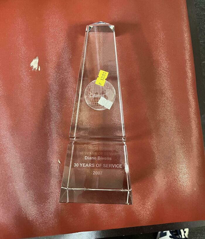 Clear glass award trophy for 30 years of service found at thrift store with price tags attached on a reddish surface.