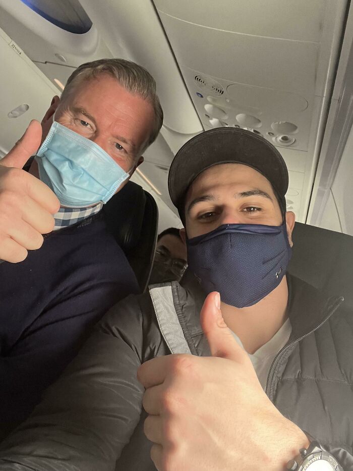 Two masked men on an airplane giving thumbs up, showing support and courage despite fear of flying.