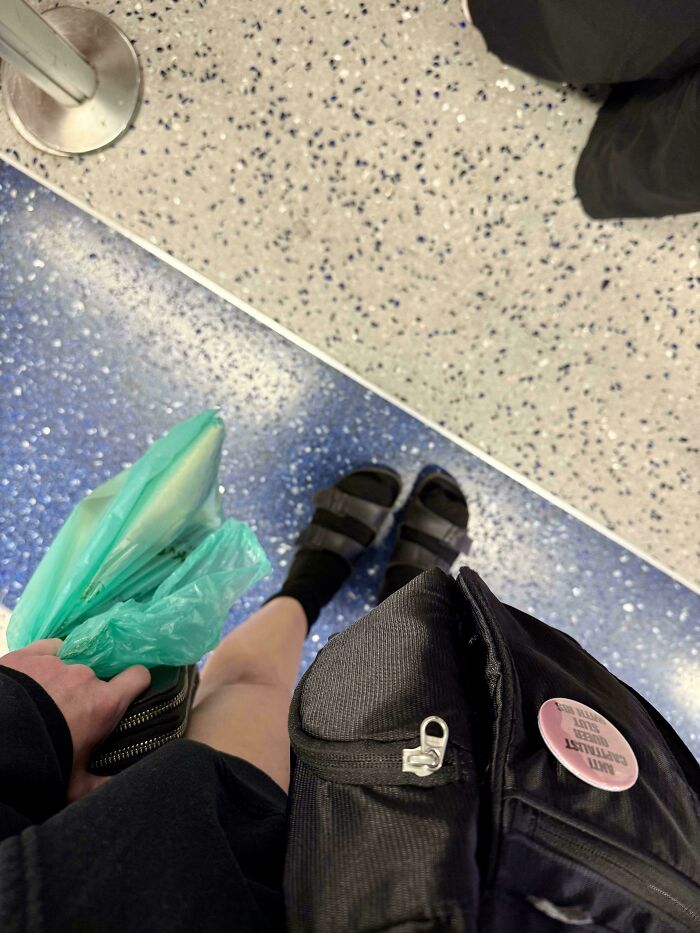 Person standing on a patterned floor holding bags, capturing a moment related to fear of flying and air travel courage.