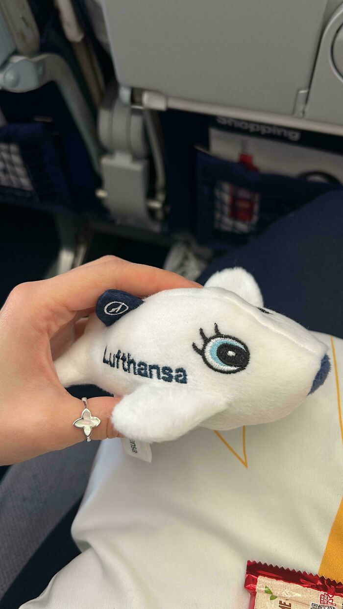 Hand holding a small Lufthansa airplane plush toy inside a plane, symbolizing overcoming fear of flying.