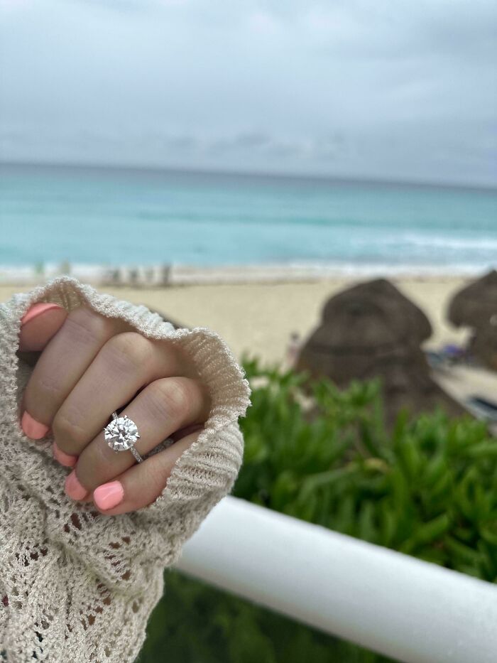 Close-up of a hand with an engagement ring near a beach, symbolizing inspiring moments overcoming fear of flying.