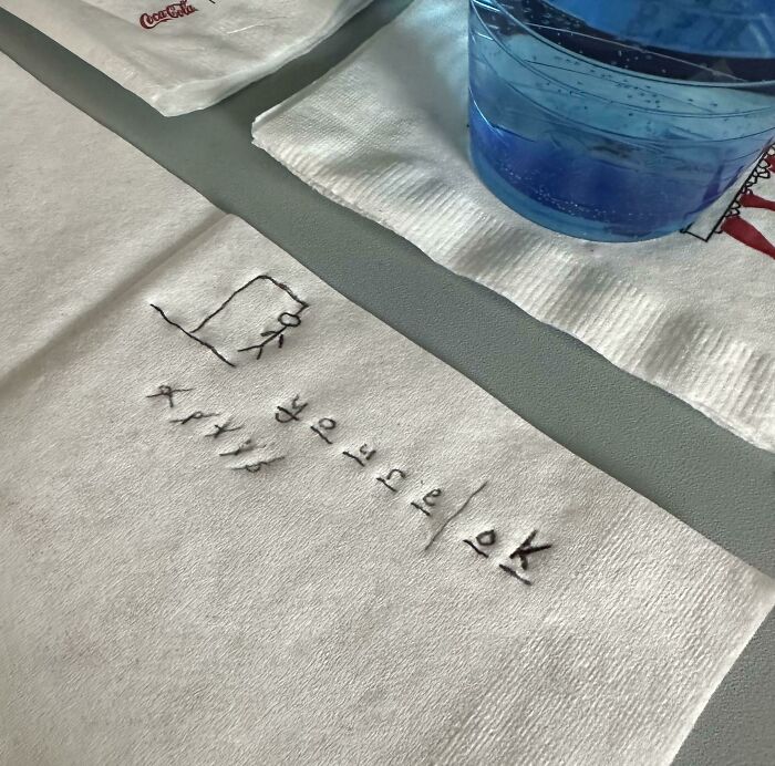Embroidered note on a plane napkin showing a hangman game, symbolizing fear of flying and overcoming it.