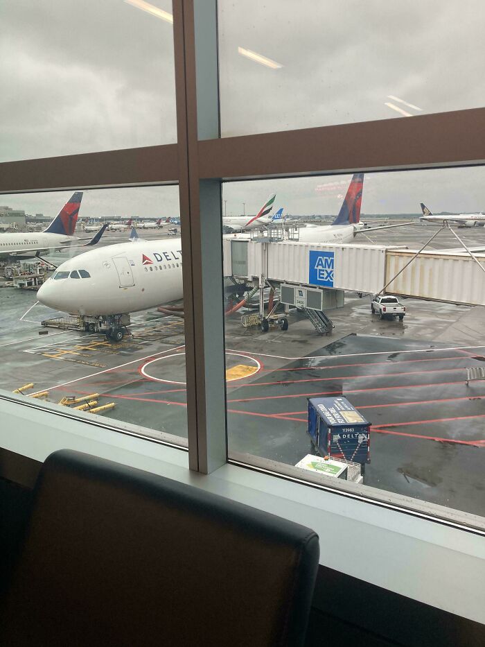 View of Delta planes at airport gate through window on a rainy day, symbolizing overcoming fear of flying and air travel challenges.