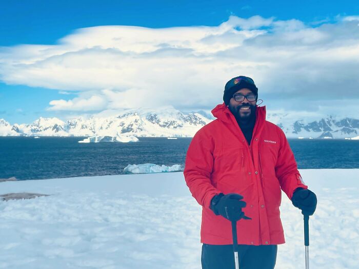 Man in a red jacket smiling outdoors in a snowy landscape, symbolizing inspiring moments overcoming fear of flying.
