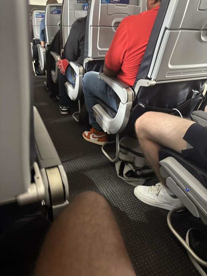 Passengers seated inside an airplane cabin showing different footwear and leg positions during a flight overcoming fear of flying.