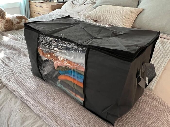 Black storage bag with folded clothes inside, placed on a bed, highlighting early Prime Day deals for home organization.