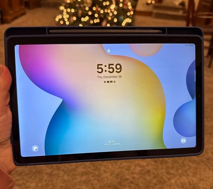 Hand holding a tablet displaying a colorful screen with the time 5:59 and early Prime Day deals background lights.