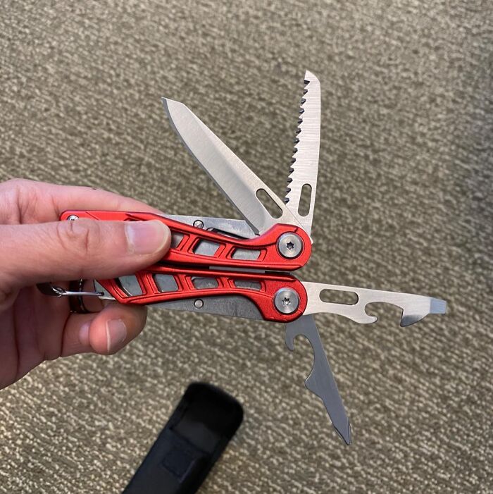 Hand holding a red multitool with knives and other tools against a beige carpet, highlighting early Prime Day deals.