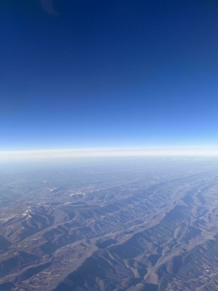 Aerial view of mountain ranges and clear blue sky captured from a plane, symbolizing overcoming fear of flying.