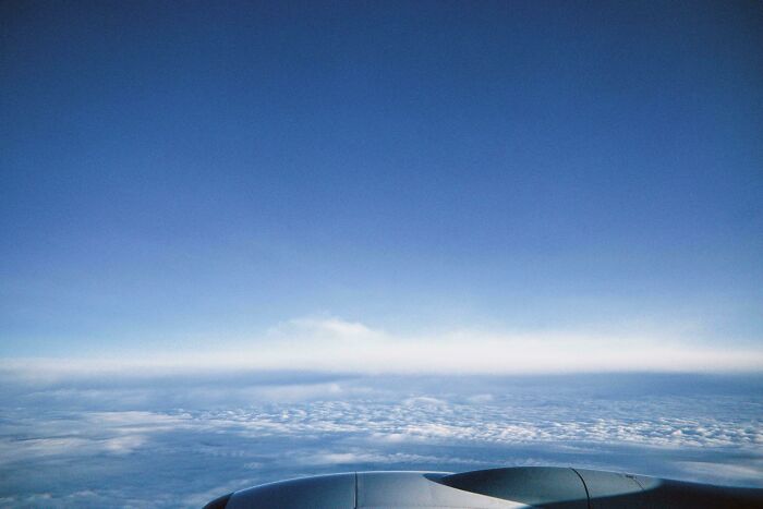 View from an airplane window showing clouds and blue sky, illustrating people overcoming their fear of flying.