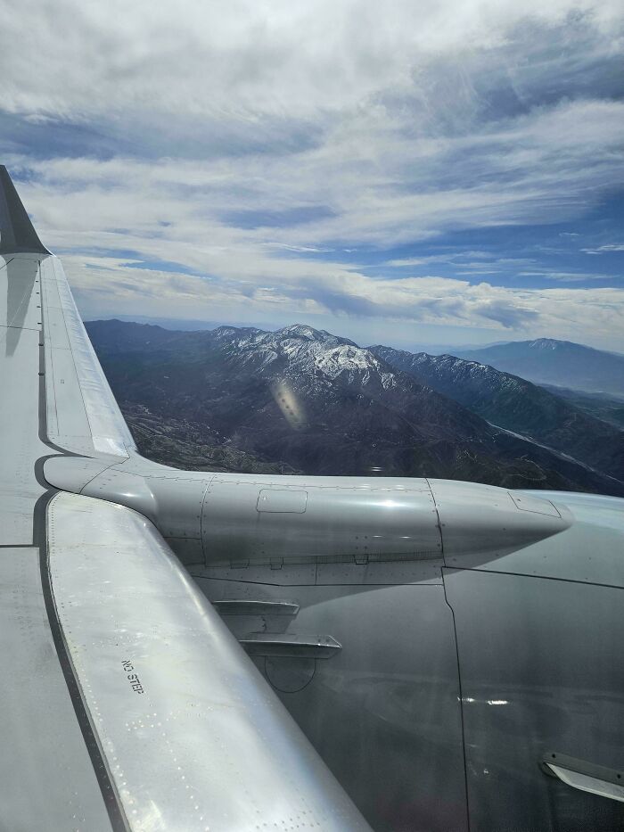 View of snowy mountains and cloudy sky from airplane window showing courage to overcome fear of flying.