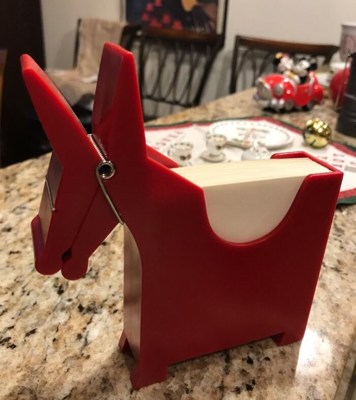 Red quirky gem shaped note holder on kitchen counter with paper notes inside and festive decor in the background.