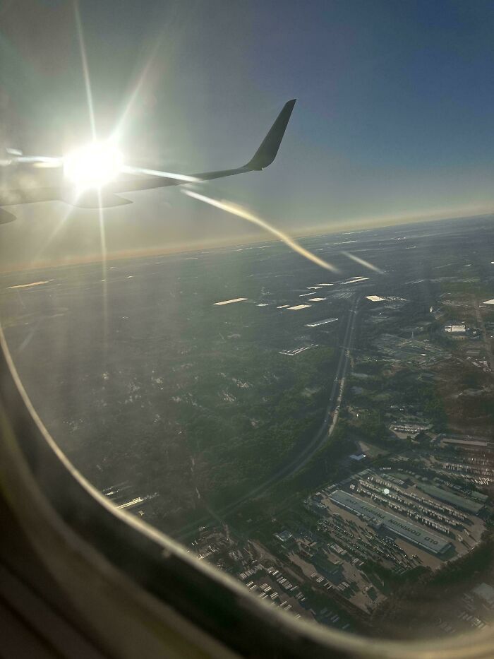 View from airplane window showing wing and sun glare over landscape, capturing moments of fear of flying courage.