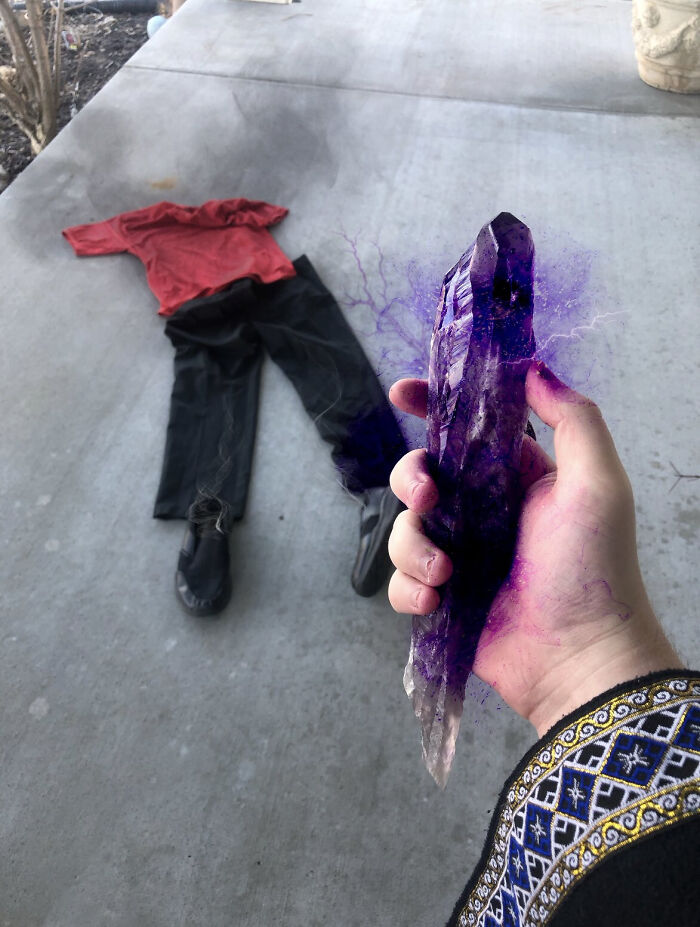 Mano sosteniendo cristal púrpura con efecto mágico, cerca de ropa en el suelo, relacionado con terribles mentirosos pillados en internet.