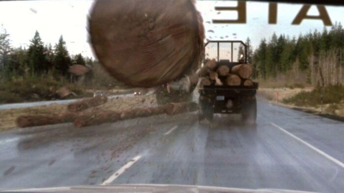 Large log flying off a truck on a wet road, capturing a creepy and scary moment from truck drivers’ lives.