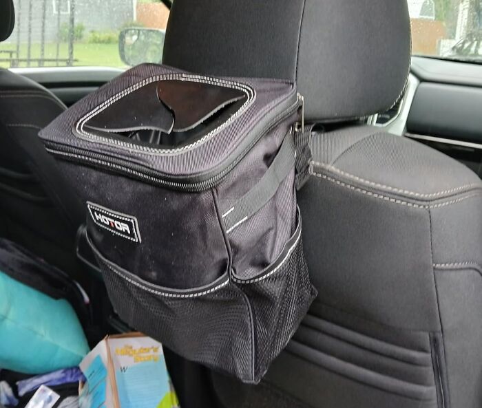 Black car organizer bag hanging on a headrest inside a vehicle, trending product in the Pandaverse virtual market.