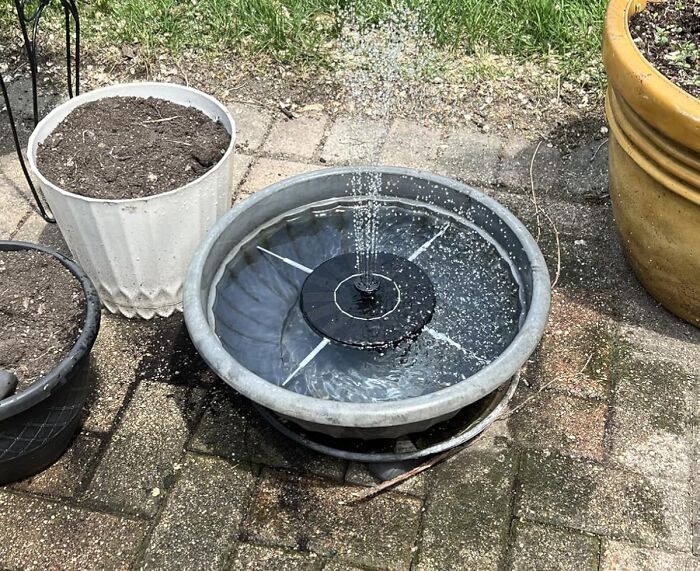 Outdoor solar water fountain in a garden setting surrounded by empty plant pots trending in the Pandaverse products.