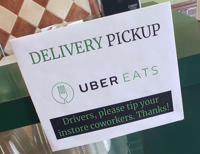 Uber Eats delivery pickup sign asking drivers to tip instore coworkers, highlighting the ridiculous tipping culture issue.