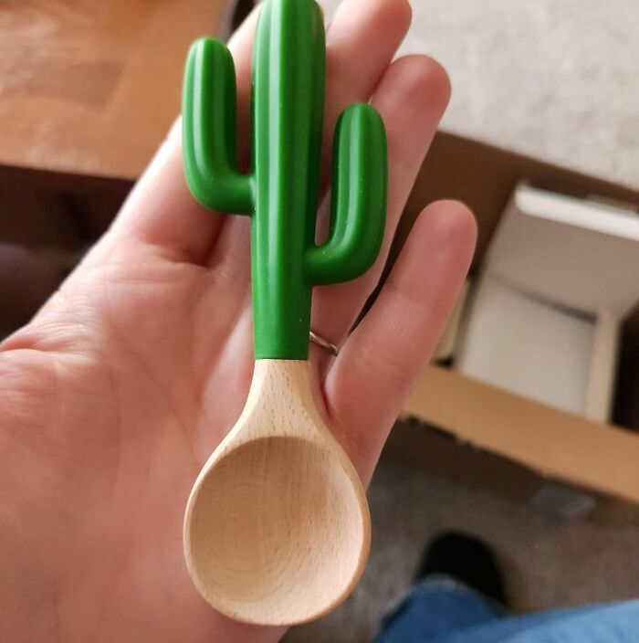 Hand holding a wooden spoon with a green cactus-shaped handle, a low-key genius novelty find.