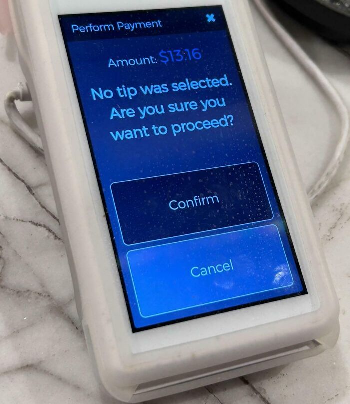 Payment terminal screen showing message asking to confirm no tip selected, highlighting tipping culture issues.