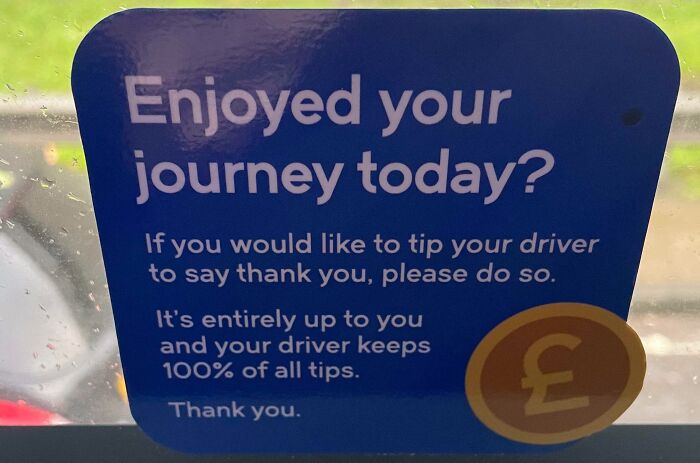 A sign on a vehicle window encouraging passengers to tip their driver, highlighting tipping culture frustrations.