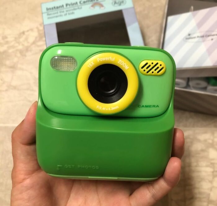Hand holding a green instant print camera, a fun gift idea for shopping for a 12-year-old kids and tweens.