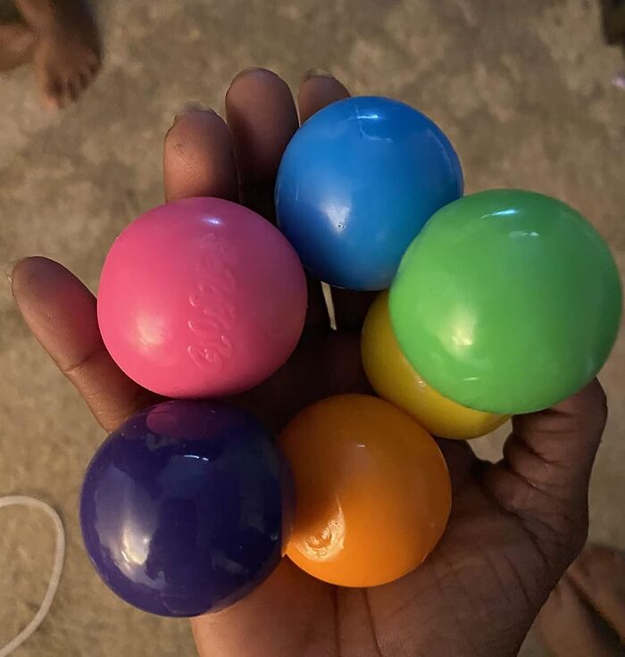 Hand holding colorful small plastic balls, representing playful items for shopping for a 12-year-old gift ideas.