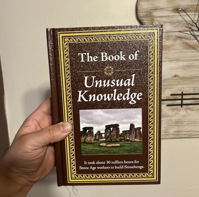 Hand holding The Book of Unusual Knowledge featuring Stonehenge, a star performer product for halftime show fans.