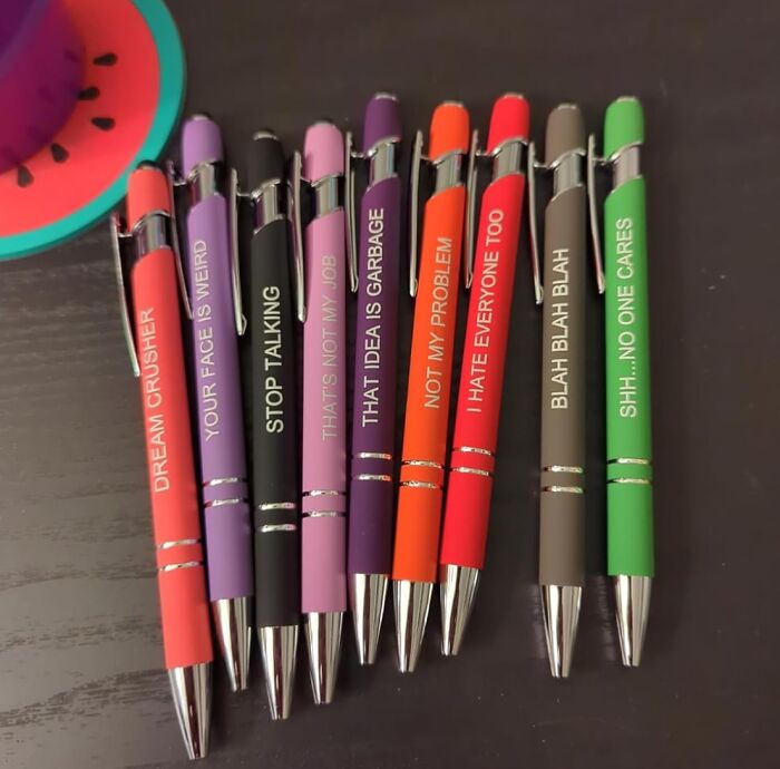 Colorful pens with funny phrases on black wooden surface, featured as star performers in the year's halftime show products.