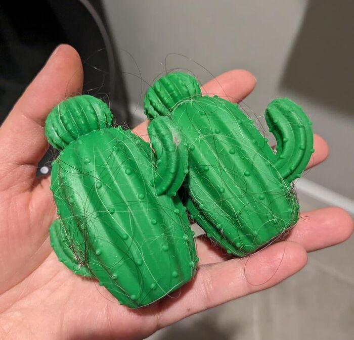 Hand holding two green cactus-shaped lint removers with hair wrapped around them, star performer products.