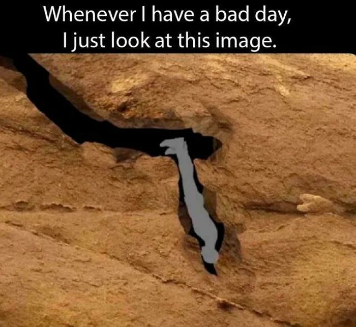 A shadow on a rock looks like a person hanging upside down, used to explain the joke in memes about bad days.
