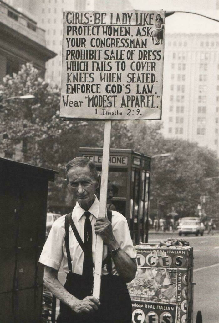 Man holding a vintage protest sign about modest apparel, representing ridiculous pics from the past that would never fly today.
