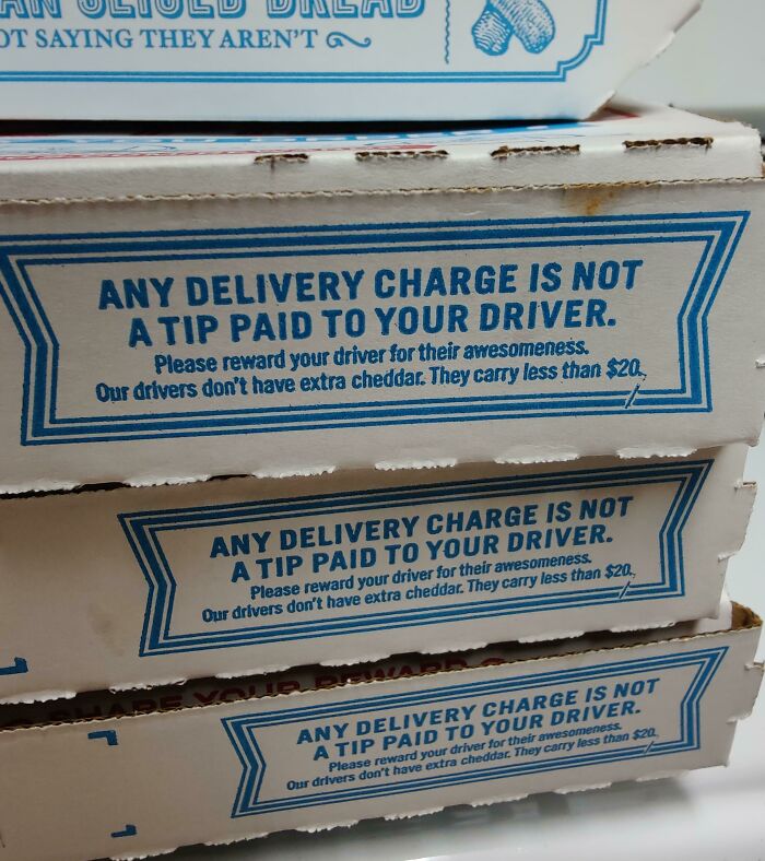 Delivery pizza boxes stacked with a message clarifying delivery charges are not tips for drivers, reflecting ridiculous fees frustration.