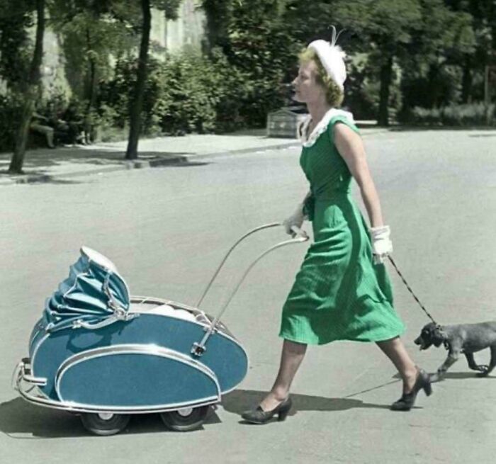 Woman in a green dress walking a dog while pushing a vintage stroller in one of the ridiculous pics from the past.
