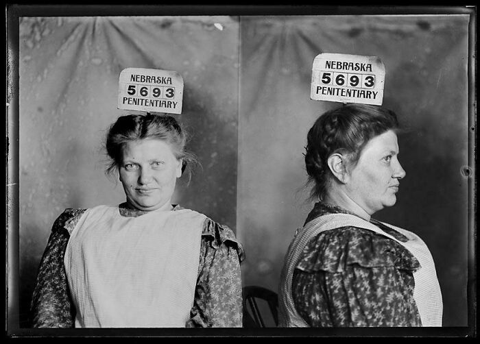 Vintage black and white prison mugshot of a woman from Nebraska penitentiary in a ridiculous past pic.