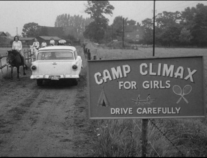 Black and white photo of a vintage car and people on horses passing a Camp Climax sign, illustrating ridiculous pics from the past.