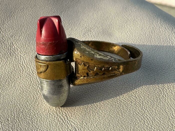 Vintage brass ring shaped like a bullet with a red plastic tip, showcasing a ridiculous pic from the past.