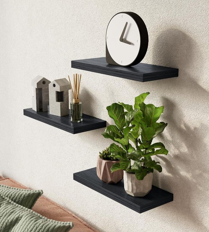 Floating black shelves on a wall holding decorative plants, a clock, and modern home decor from Amazon wishlist finds.