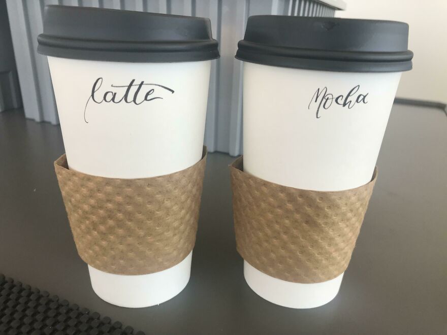 Two coffee cups labeled latte and mocha in perfect handwriting examples on white paper cups with brown sleeves.