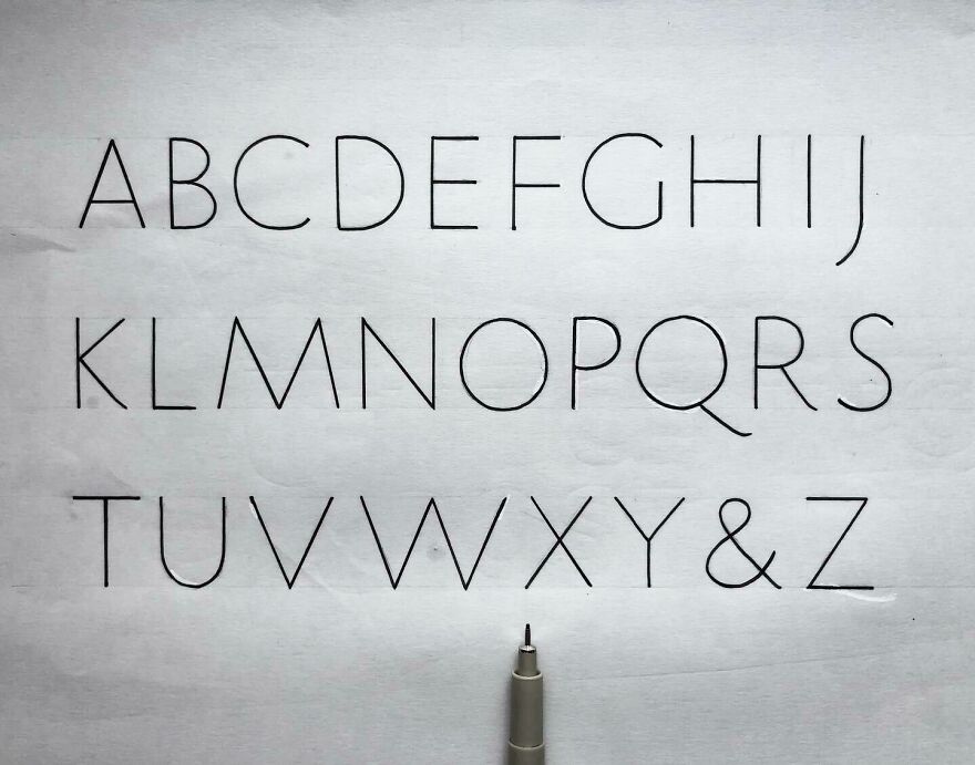Perfect handwriting example showing neatly written uppercase alphabet letters with a pen on white paper.