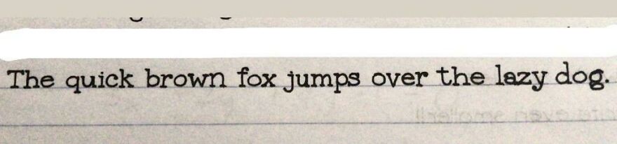 Perfect handwriting example of the sentence The quick brown fox jumps over the lazy dog on lined paper.