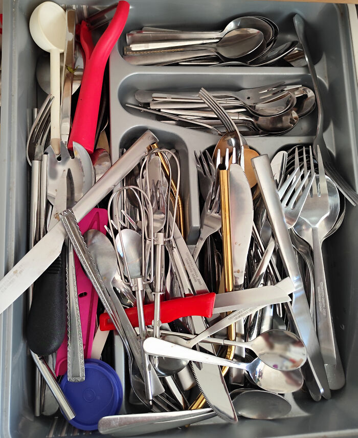 Cluttered kitchen drawer filled with mixed utensils, highlighting clueless partner organization in hilarious photos.