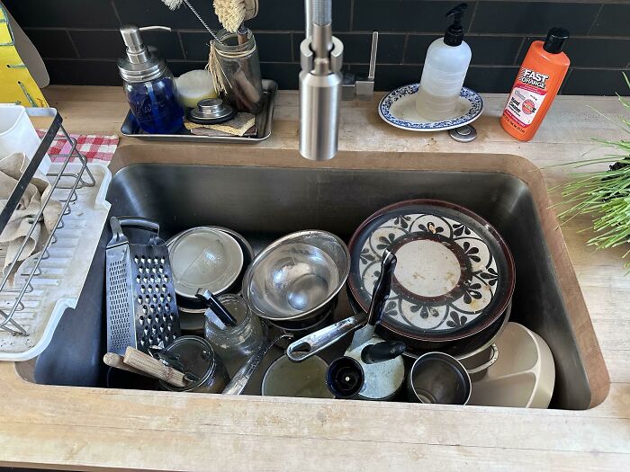 Kitchen sink full of dirty dishes and utensils, showcasing hilarious photos of clueless partners struggling with chores.