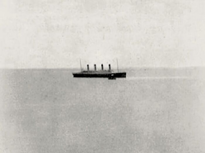 Black and white photo of an old ship on calm water, evoking creepy and unsettling vibes from the past.