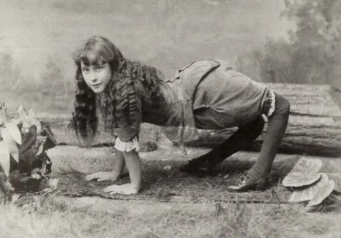 Black and white vintage photo of a young woman posing on all fours, an incredibly creepy and unsettling image from the past.