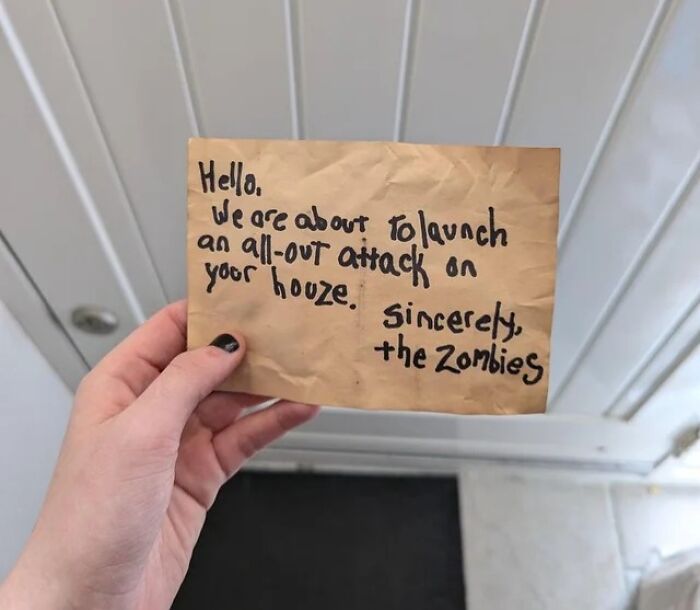 Person holding a humorous handwritten note mocking internet lies with a funny and absurd message from zombies.