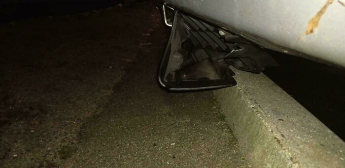 Car side mirror smashed on a curb, illustrating a hilarious example of clueless partner mistakes.
