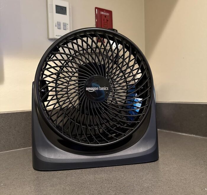 Black Amazon Basics desk fan on a countertop representing Prime Day deals under $25 to keep your bank account safe.