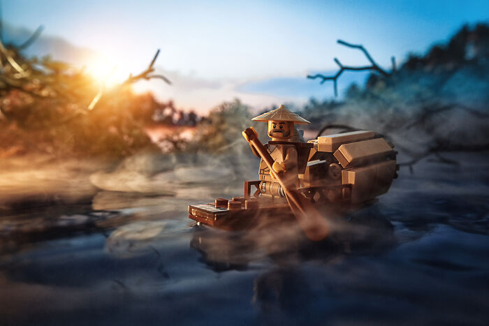 LEGO figure paddling a boat through misty water at sunset, showcasing creative Hollywood-level LEGO scenes photography.
